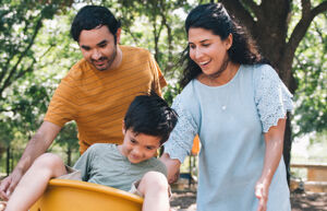 parents pushing a kid in a swing